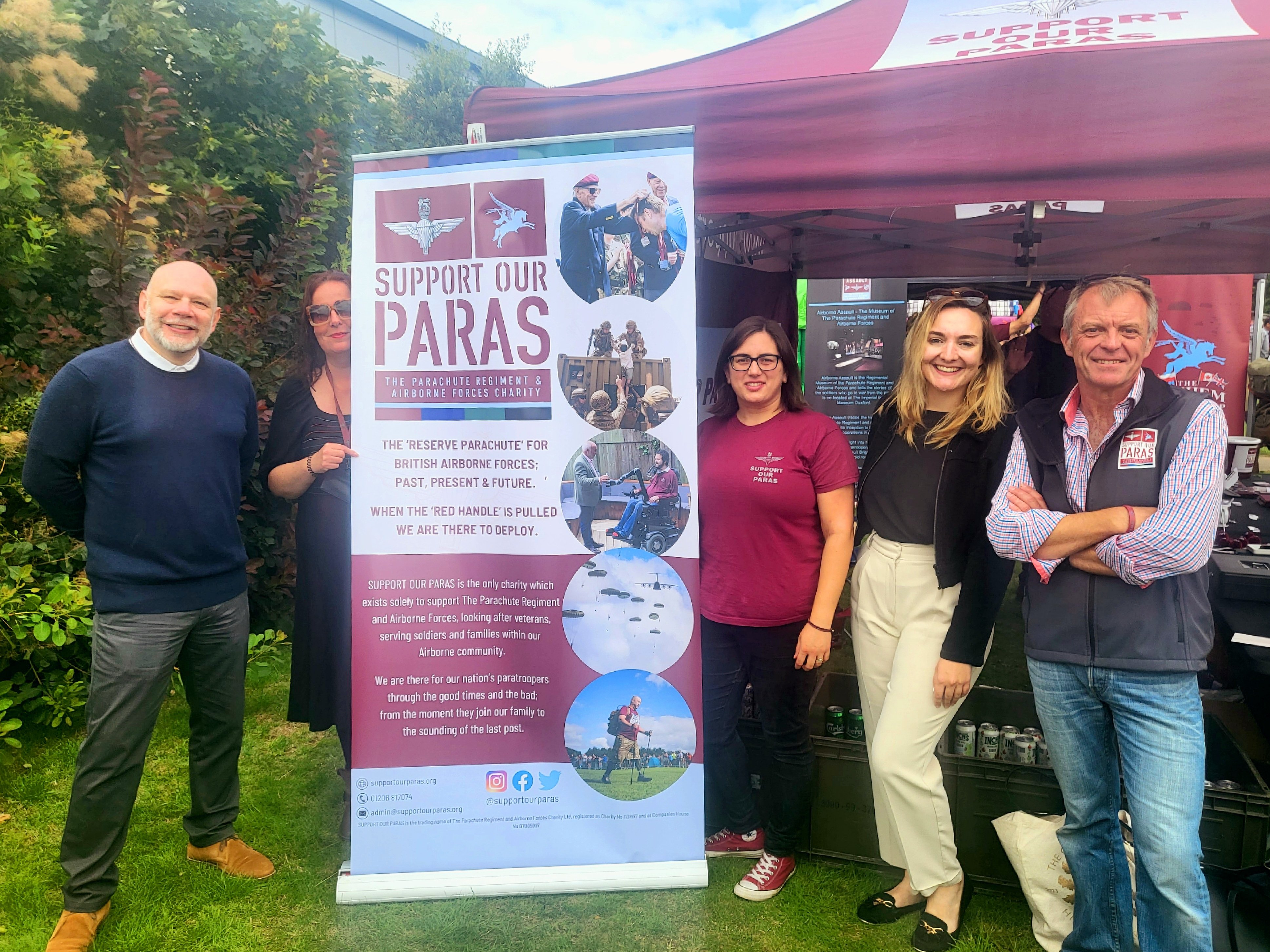 People from Irwin Mitchell and Support Our Paras stand in front of a banner.
